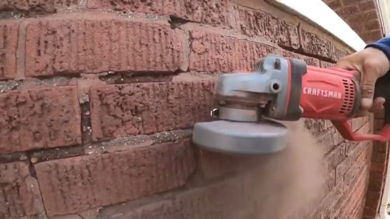 Grinding the old mortar out of the bed joints on a red brick wall before repointing