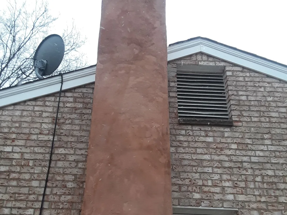 Tall parged chimney stack running up the side of a house