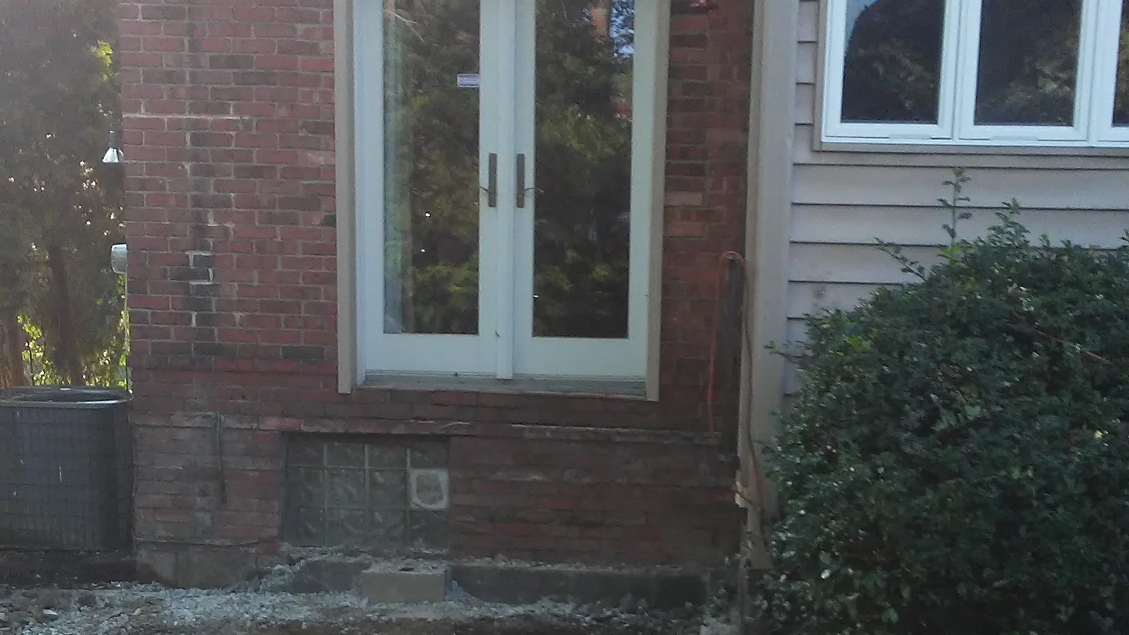 Patio slab removed beside a brick house, leaving a clean gravel base
