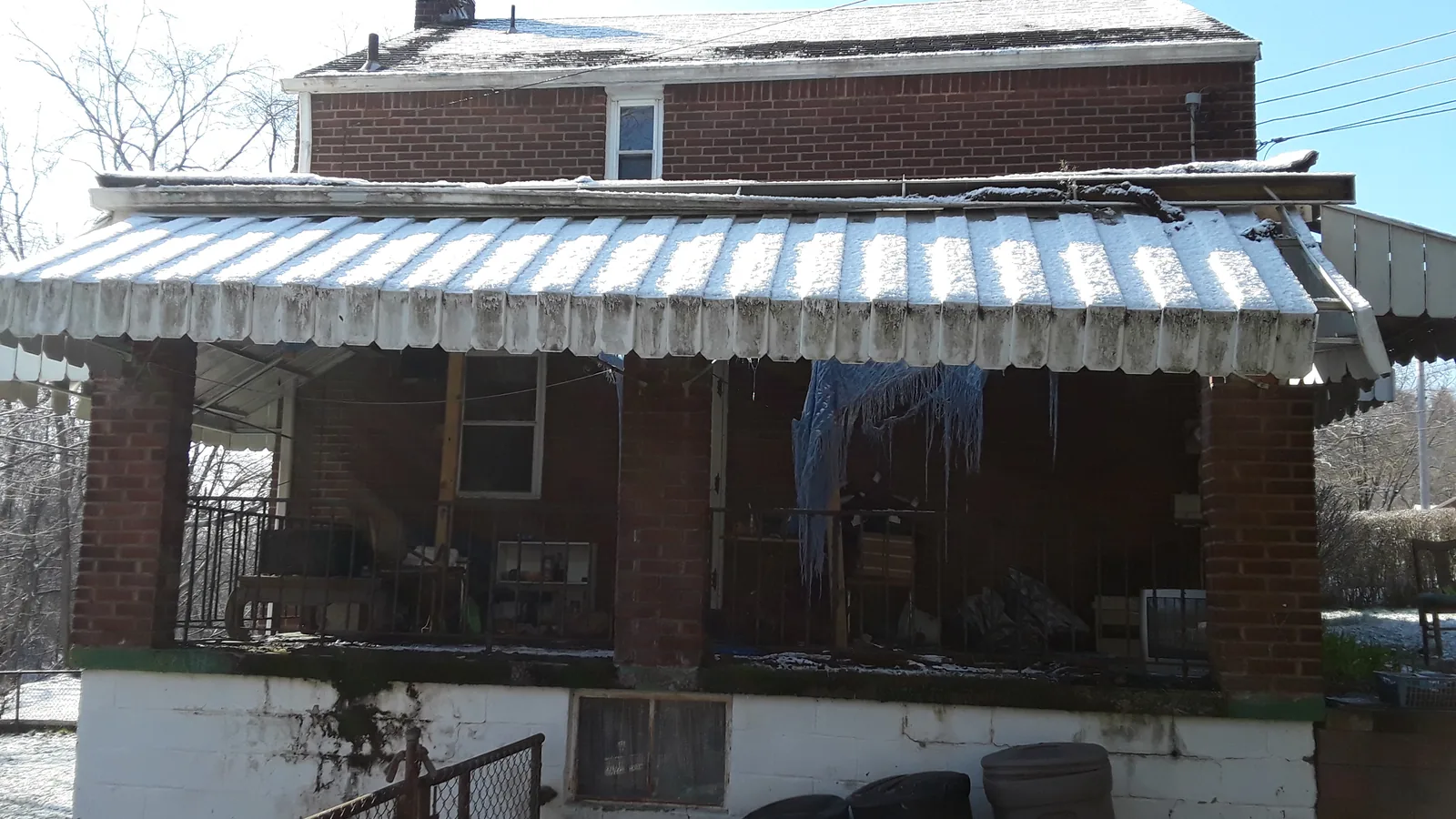 House with a covered porch and awning standing before demolition