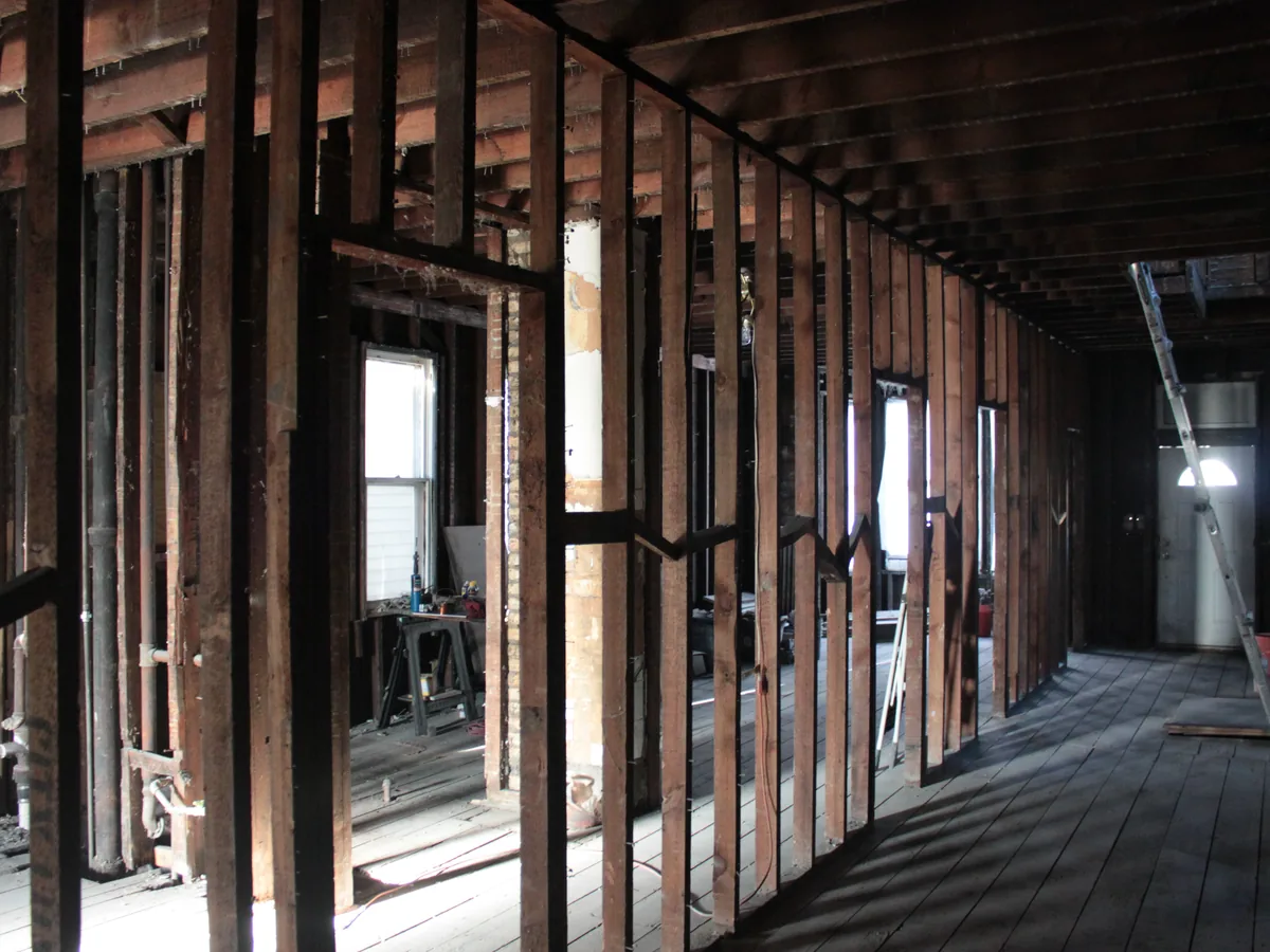House interior gutted to the studs and ceiling joists with the old floorboards still in place